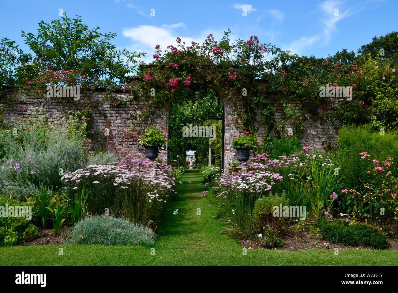 Passage voûté et frontières floral dans un jardin typiquement anglais, UK Banque D'Images