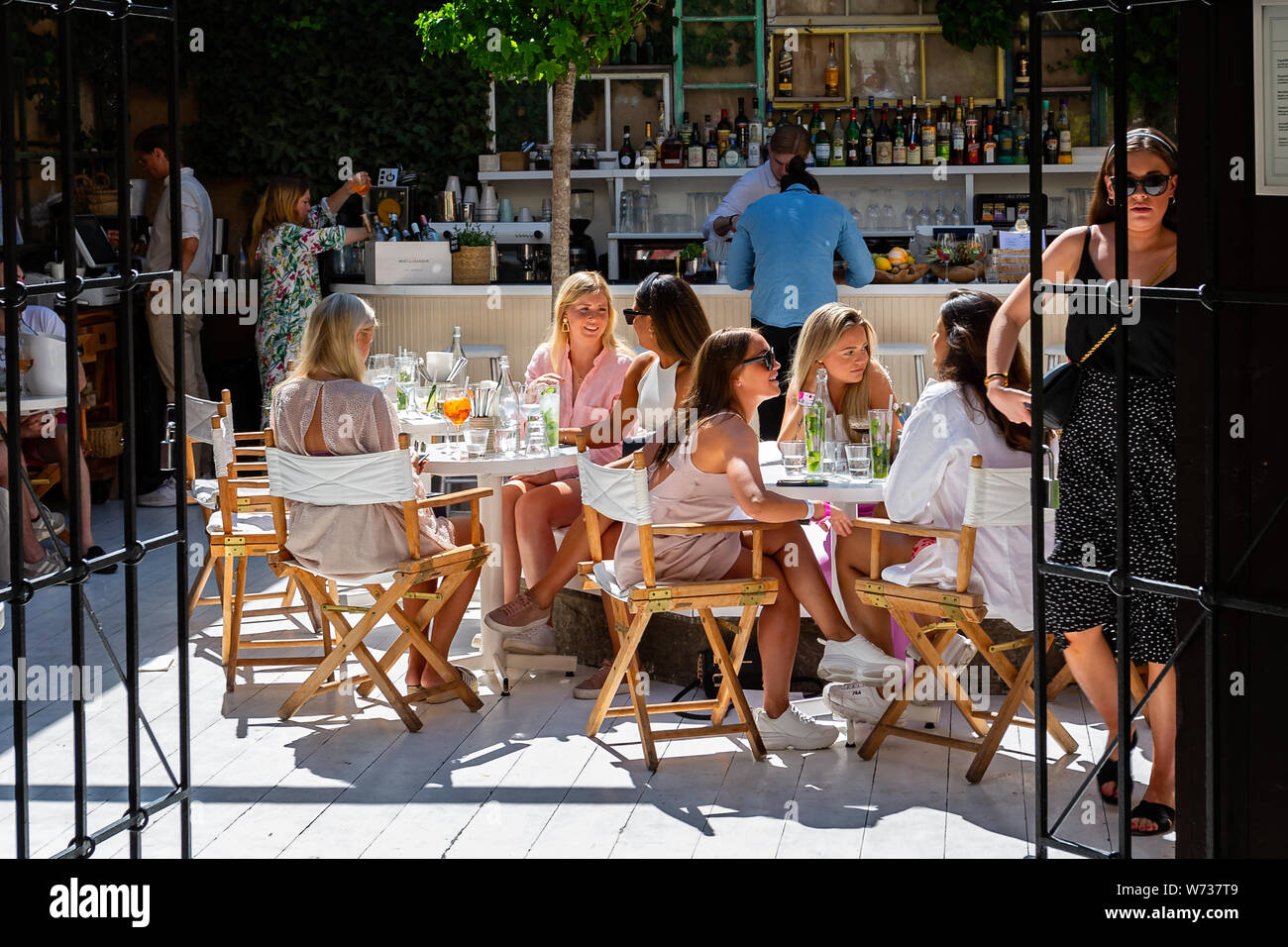 Groupe de belles jeunes femmes s'assit à table pour discuter et boire des cocktails à Visby, Gotland, Suède le 20 juillet 2019 Banque D'Images