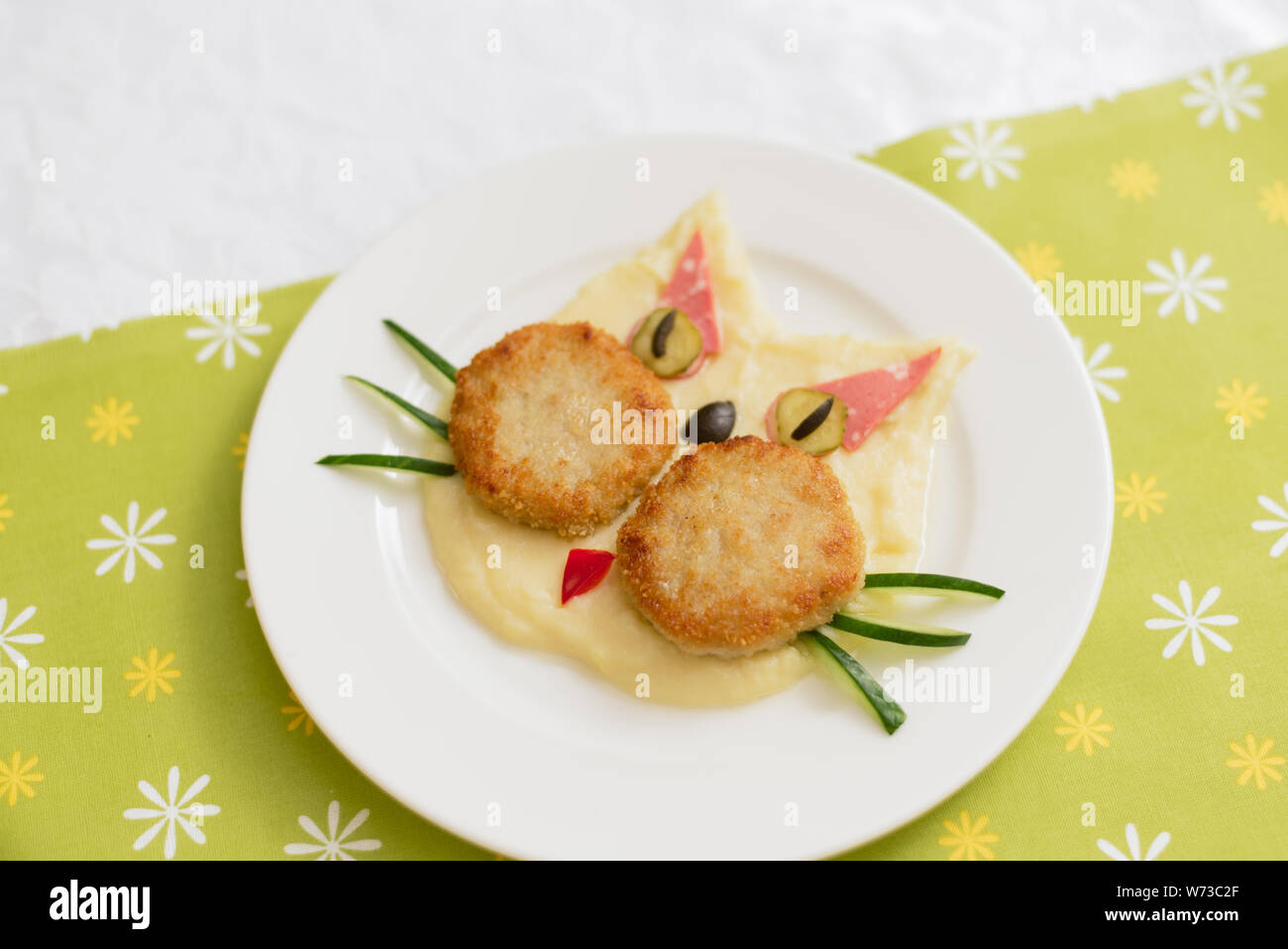 Purée bébé sous la forme d'un chat. Purée de pommes de terre. Menu enfant sur un fond vert Banque D'Images