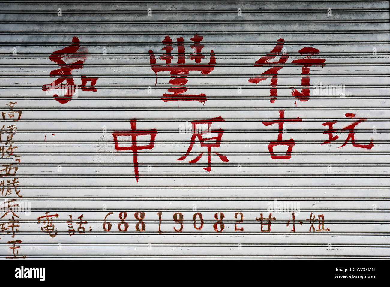 Les caractères chinois rouge sur une porte d'enroulement à Sheung Wan, Hong Kong Banque D'Images
