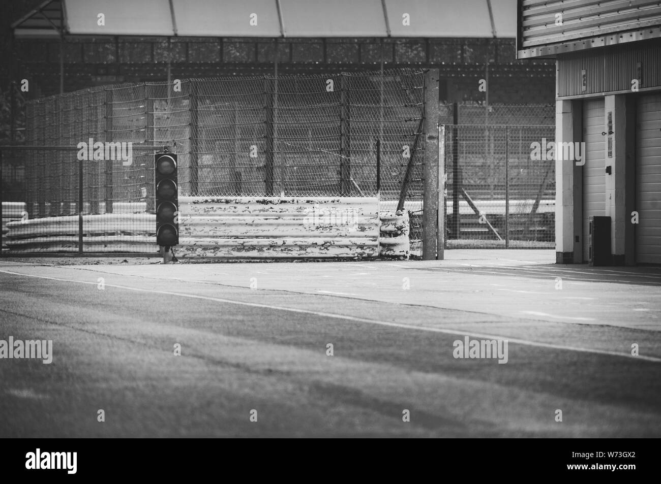 Les images en noir et blanc du feu de circulation à la sortie de la voie des stands à original déserte de Silverstone. Garages sur la droite de l'image. Banque D'Images
