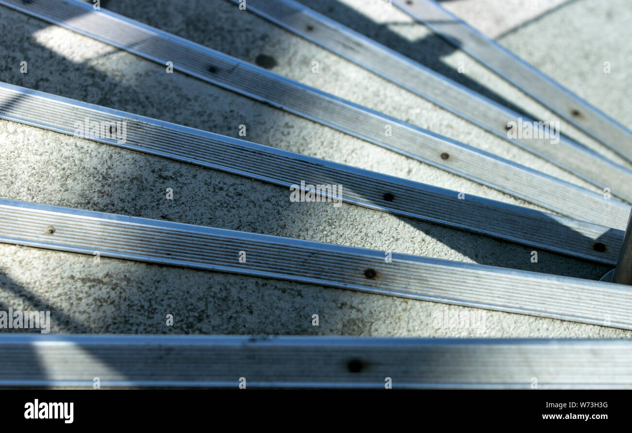 Close up portrait d'une série de mesures concrètes de protection métallique avec des bandes à bords de descendre dans un trimestre, en spirale sous les ombres et matin Banque D'Images
