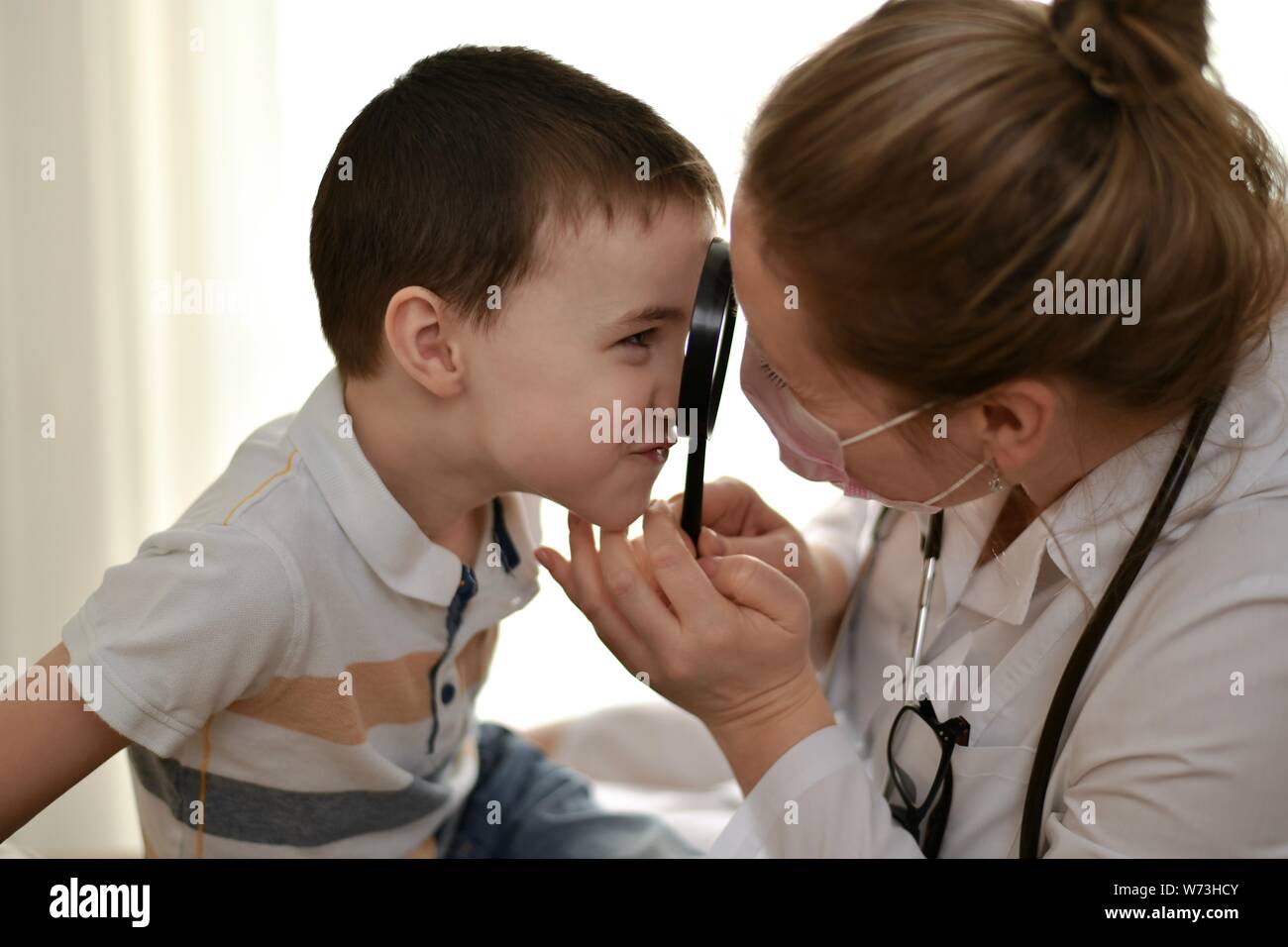 L'enfant et le médecin plaisantez, contemplant les uns les autres à travers une loupe et le toucher. Banque D'Images