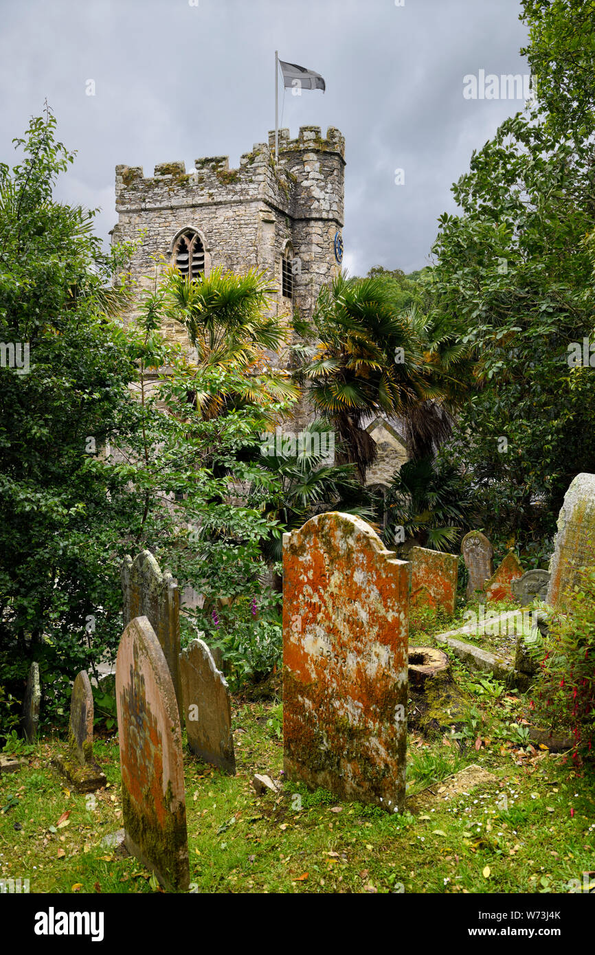 Pierres tombales de l'ancien cimetière à flanc de colline avec une tour de l'église de St Just à St Just in Roseland Cornwall Angleterre Banque D'Images