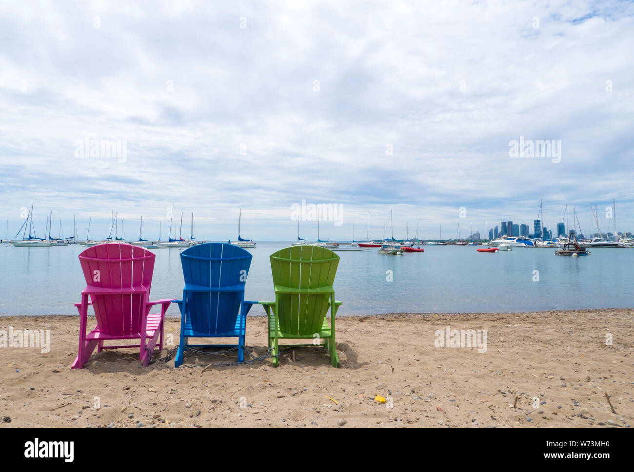 Muskoka Cottage multicolores des chaises sur le sable la plage donnant sur le port et le centre-ville d'Etobicoke, dans l'arrière-plan Banque D'Images
