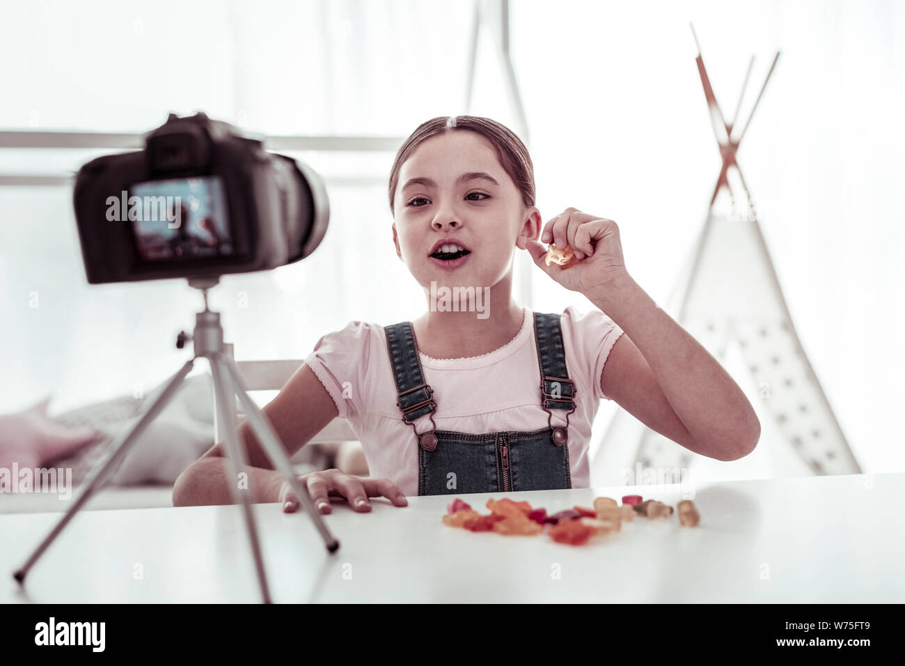 Nice girl eating sweets joyeux devant la caméra Banque D'Images