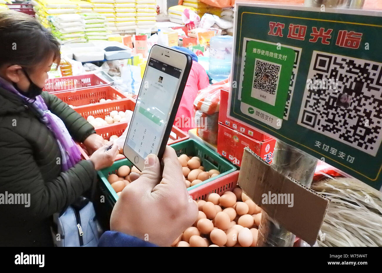 Un client numérise un QR code via le service de paiement mobile de Tencent Wechat sur son smartphone, pour payer son achat à un marché libre dans la ville de Lianyungang Banque D'Images