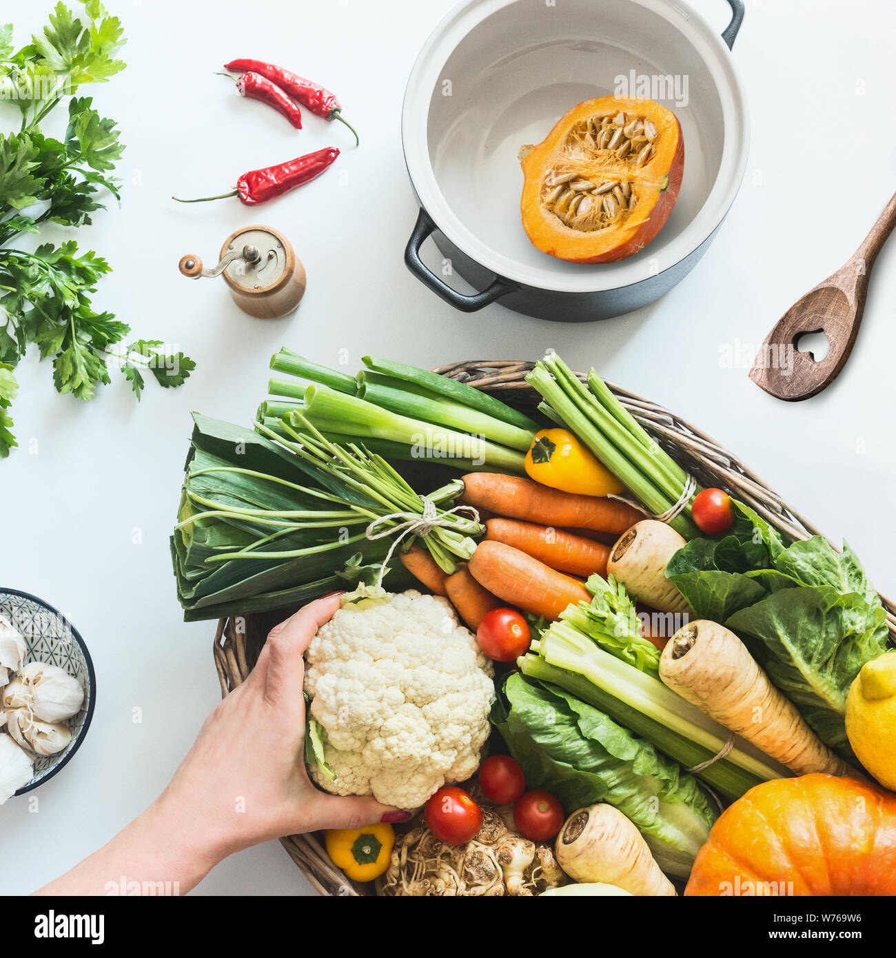 La cuisine de saison en bonne santé. La cuisine d'automne à la citrouille. Femme hand holding ingrédients sur bureau blanc avec divers ferme bio légumes colorés , pot Banque D'Images