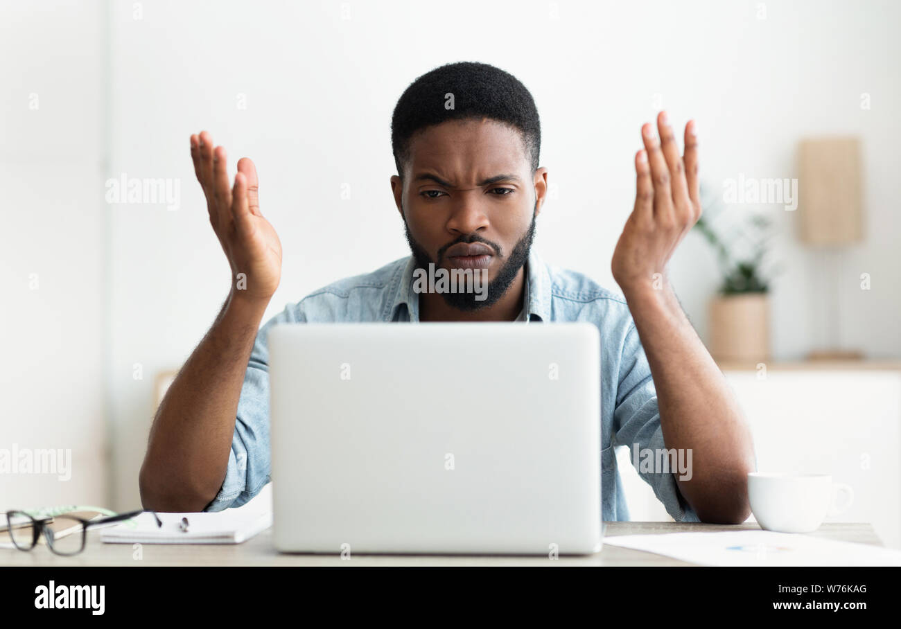 Souligné africains-américains businessman looking at laptop screen in modern office Banque D'Images