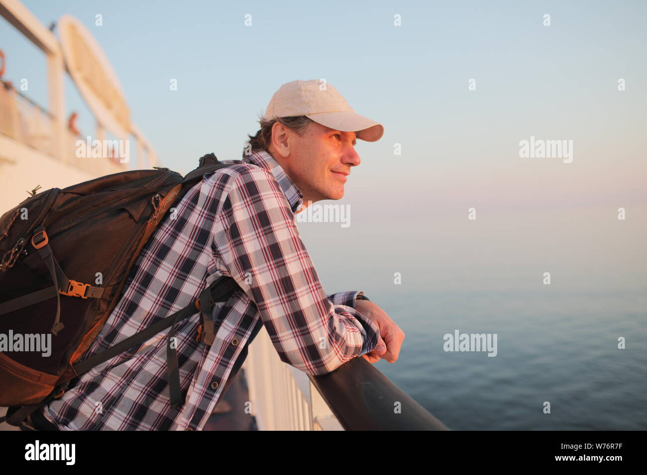 L'homme admire le coucher du soleil sur la mer le pont d'un navire de croisière Banque D'Images