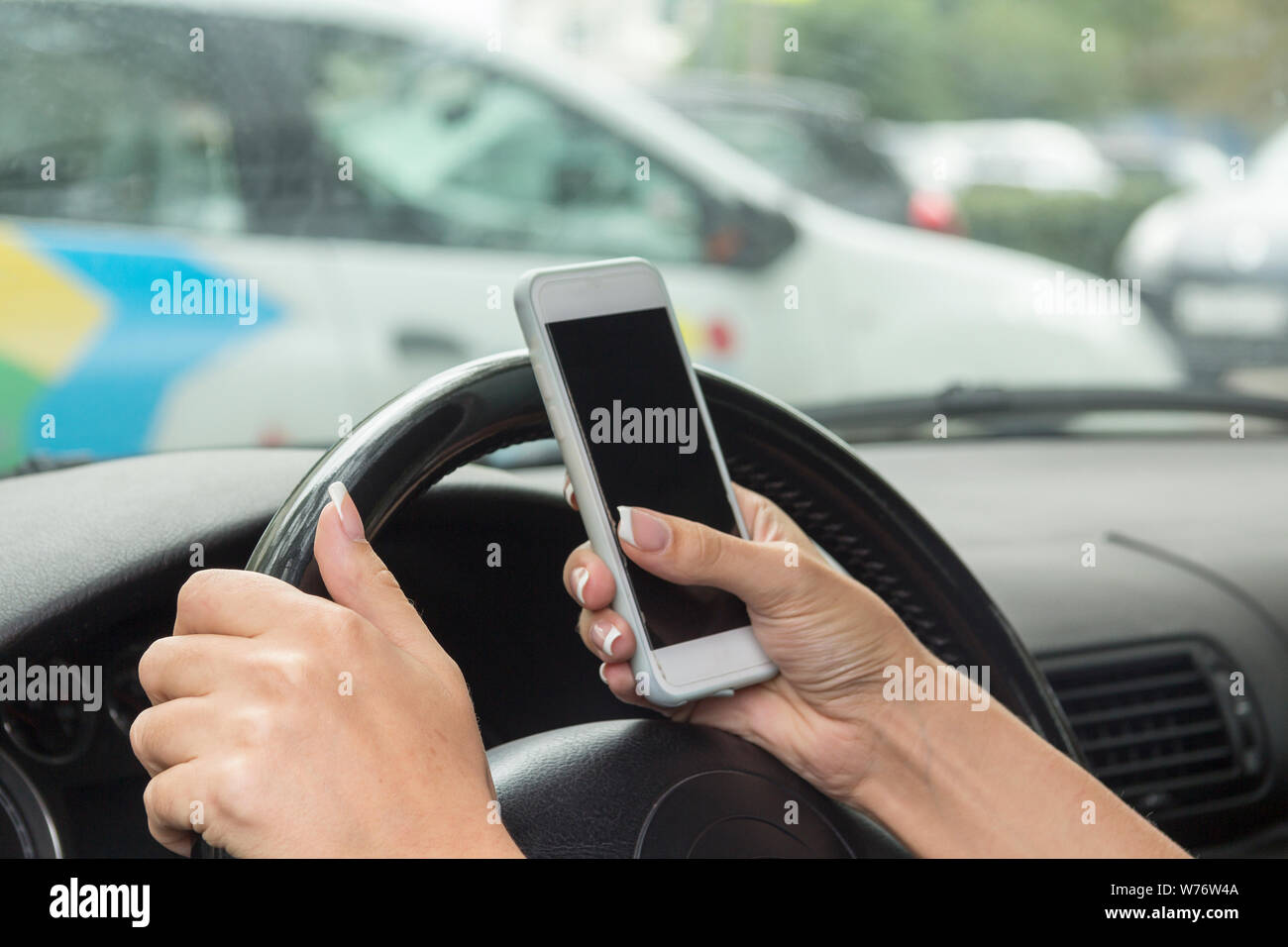 Fille avec un téléphone mobile derrière le volant dans le salon de voiture Banque D'Images