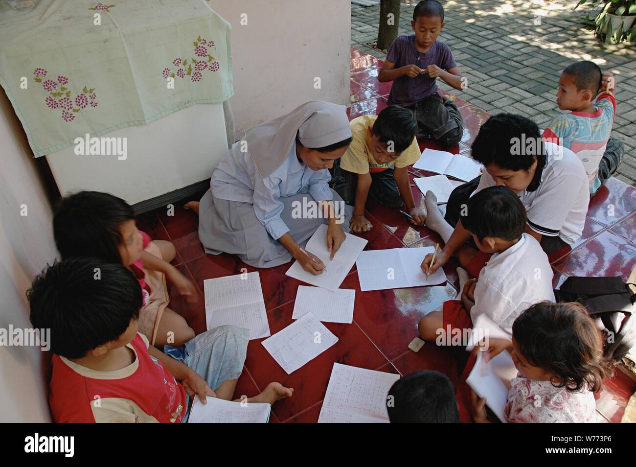 Bogor, Java ouest, Indonésie - Juillet 2019 : une religieuse catholique de Ordo FMM (Franciscaines Missionnaires de Marie) apprendre aux enfants à lire et à écrire. Banque D'Images