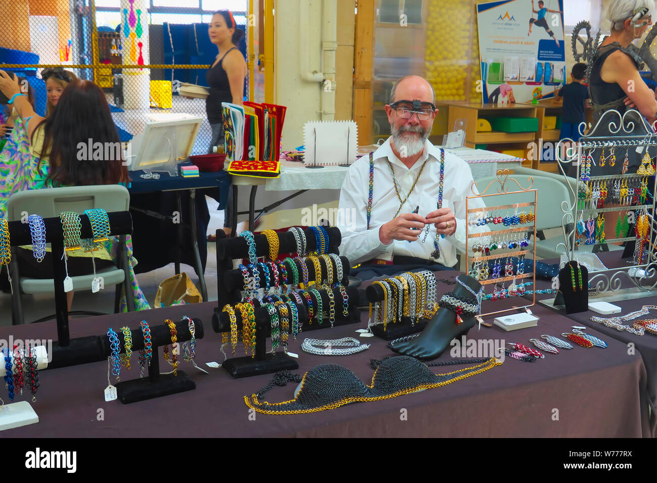 Un homme de la bijouterie vender à une foire artisanale de création de bijoux de chaîne. Banque D'Images