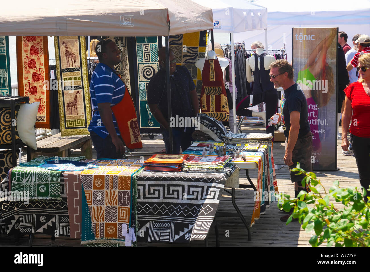 Shopper's à la recherche à l'African tapis conçu lors d'une foire artisanale. New Westminster, Colombie-Britannique, Canada. Banque D'Images