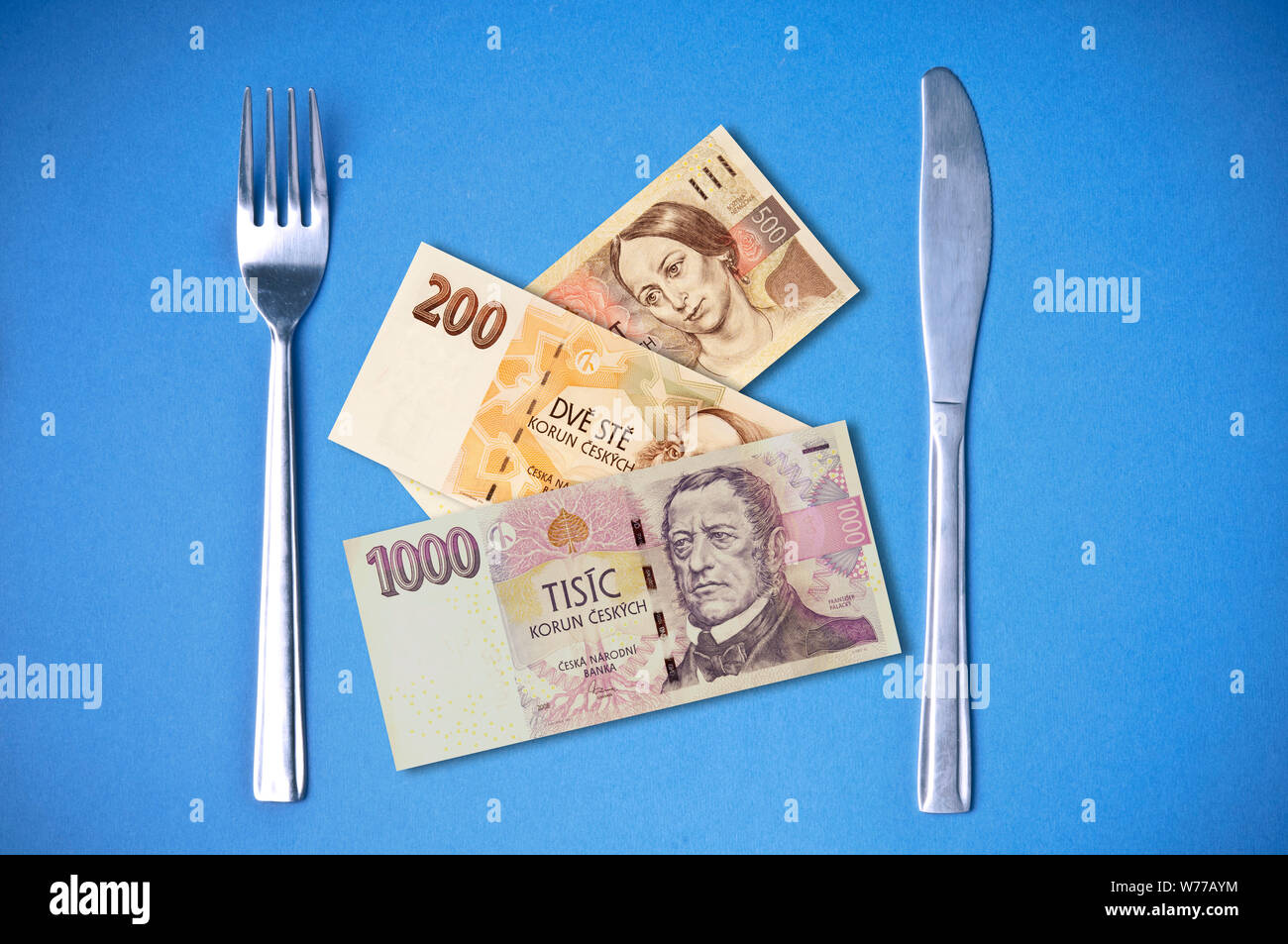 Image conceptuelle de fourchette et couteau avec couronne tchèque billets en euros au lieu d'aliments Banque D'Images