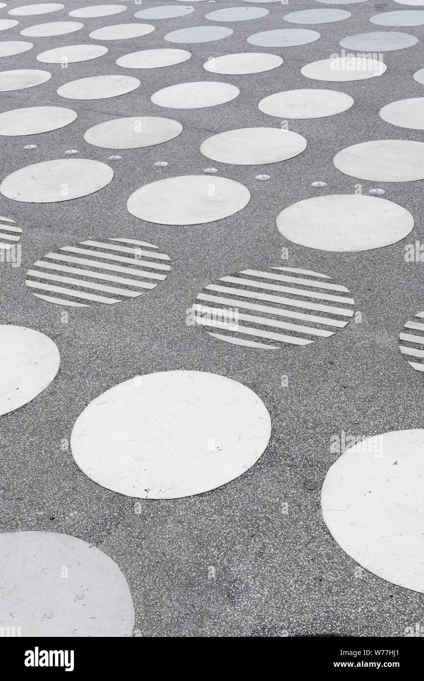 Un carré de béton avec un motif de cercles blancs symétriques en perspective. Banque D'Images