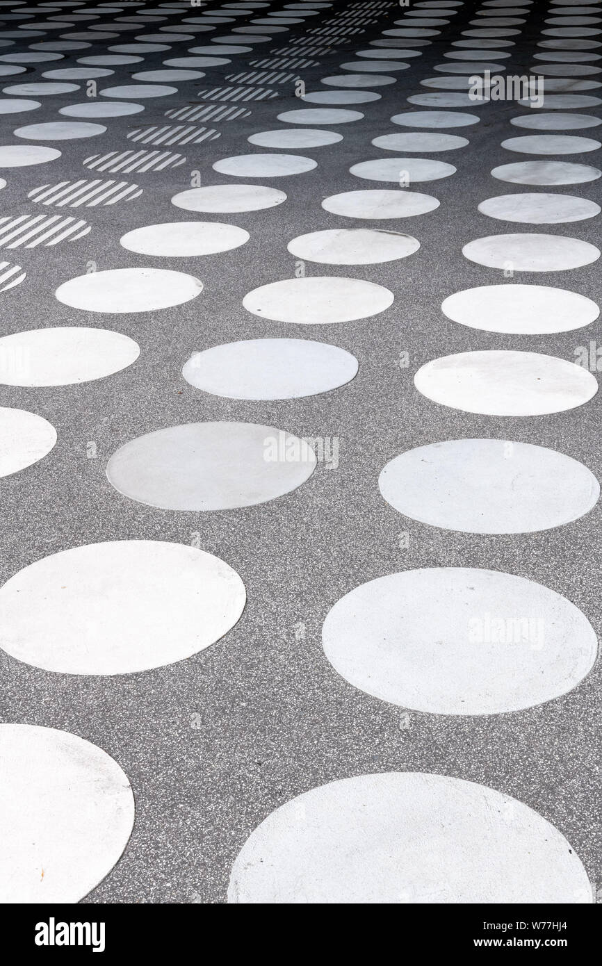 Un carré de béton avec un motif de cercles blancs symétriques en perspective. Banque D'Images