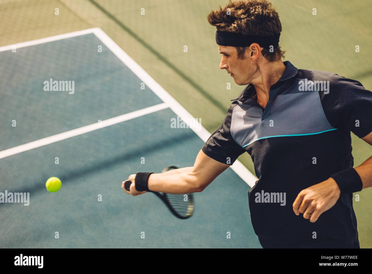 Joueur de tennis professionnel frapper forehand sur surface dure. Jeune homme dans les vêtements de sport en jouant au tennis sur le court de tennis. Banque D'Images