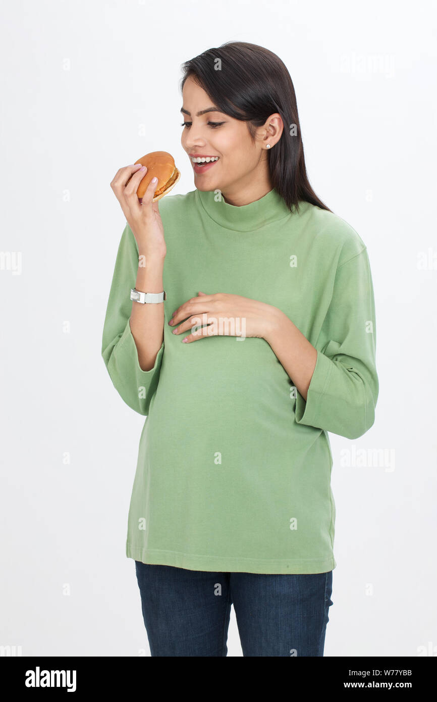 Pregnant woman eating hamburger Banque D'Images