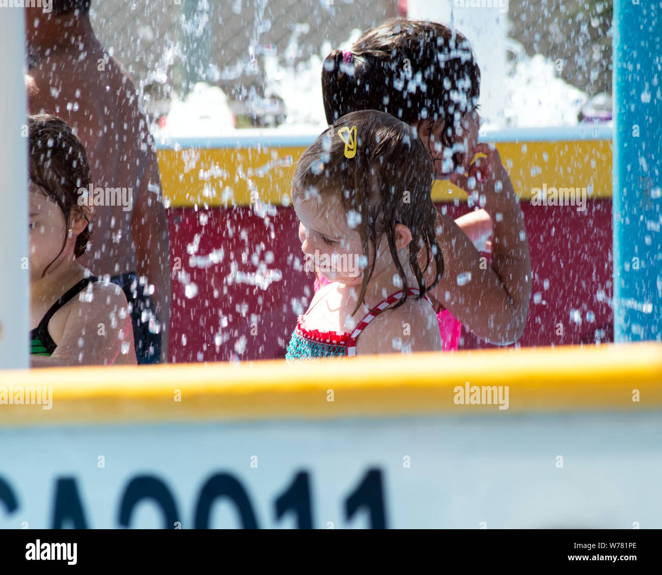Les enfants bénéficient d'une douche rafraîchissante de l'eau à la Texas State Aquarium's splash park à Corpus Christi, Texas USA. Banque D'Images