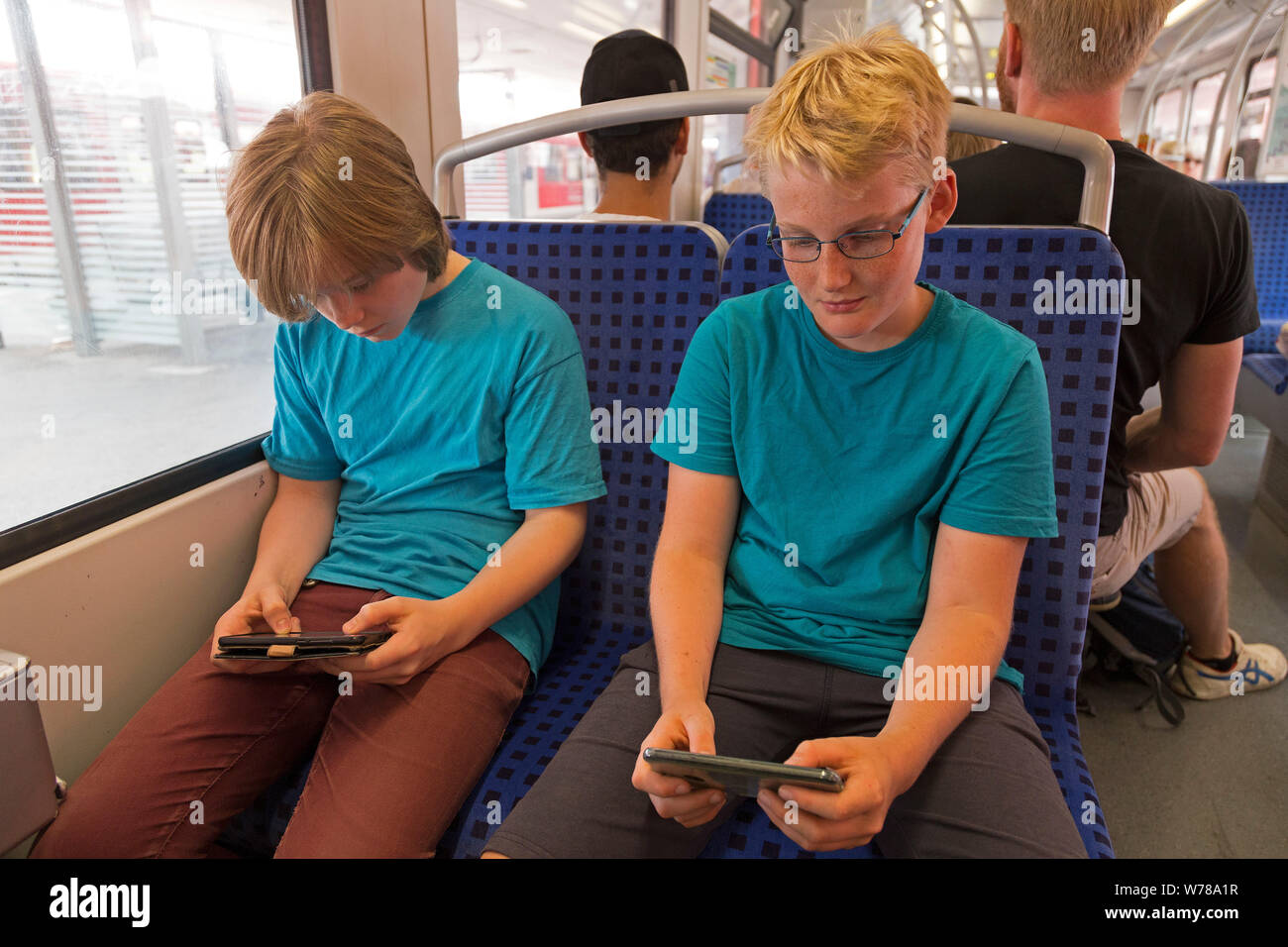 Adolescents jouant avec les téléphones mobiles sur le réseau express régional, Hambourg, Allemagne Banque D'Images