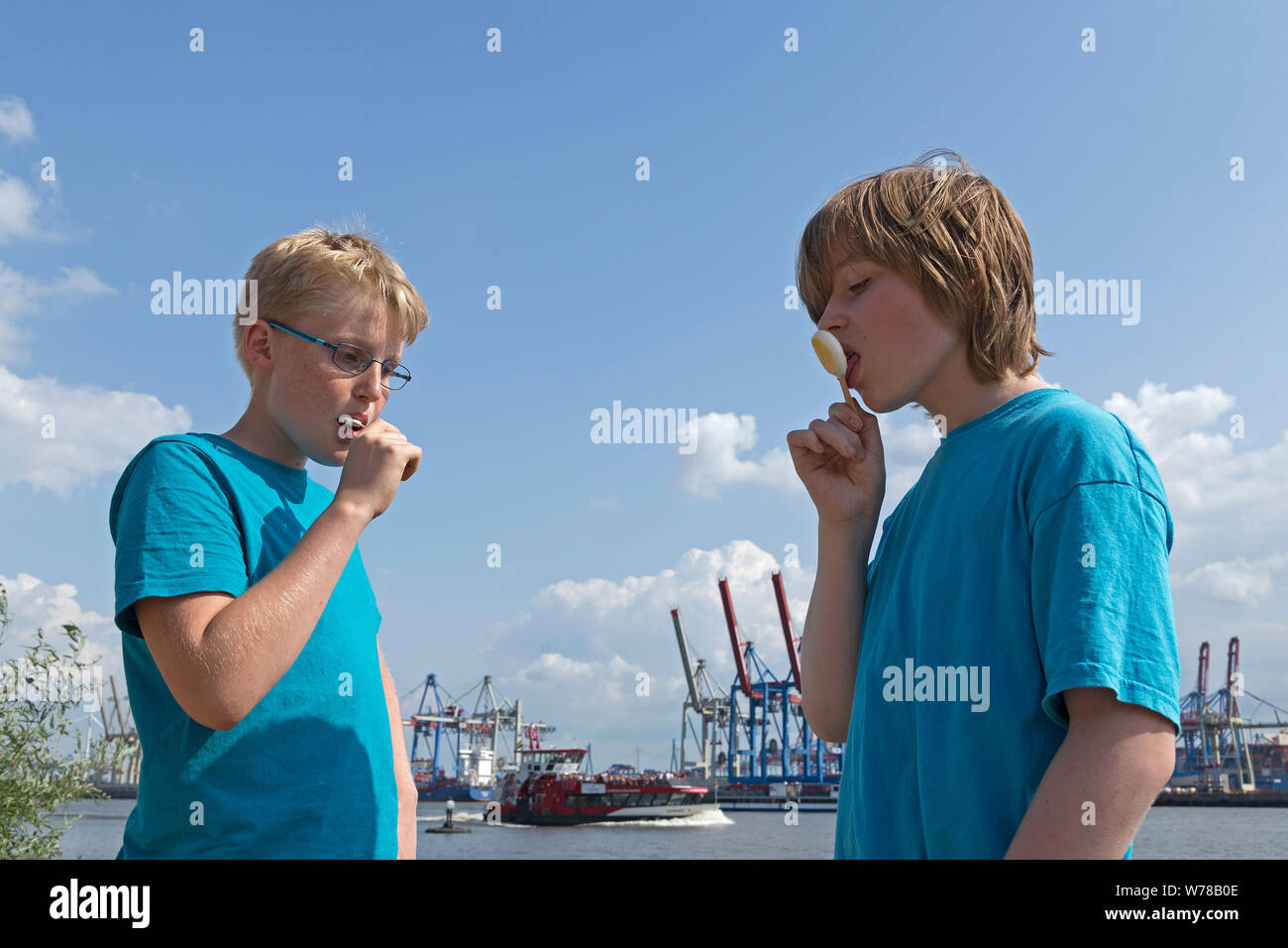 Les adolescents la consommation de crème glacée sur la plage de Oevelgönne inf/d'un terminal à conteneurs Burchard Kai, Hambourg, Allemagne Banque D'Images