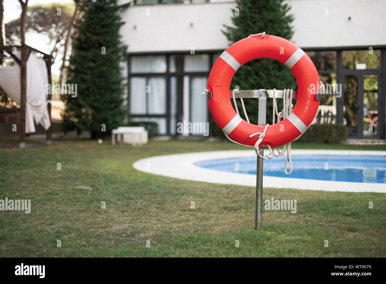 Gros plan photo d'un flotteur en caoutchouc orange et blanc, debout dans une zone de sécurité avec des cordes dans une piscine Banque D'Images