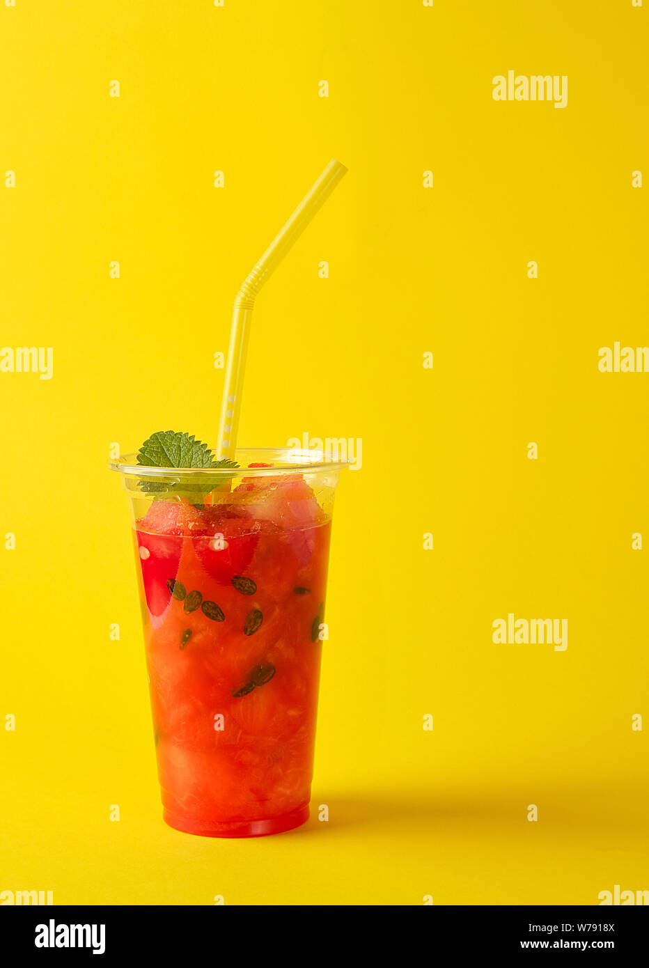 De smoothie pastèque rouge mûr dans une tasse en plastique, Close up, fond jaune Banque D'Images