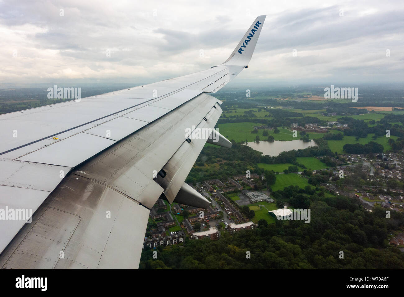 Les volets de l'aile se préparent à ouvrir sur un Boeing 737 de Ryanair - 800 pour un atterrissage sous la pluie sur la piste de l'aéroport de Manchester Banque D'Images