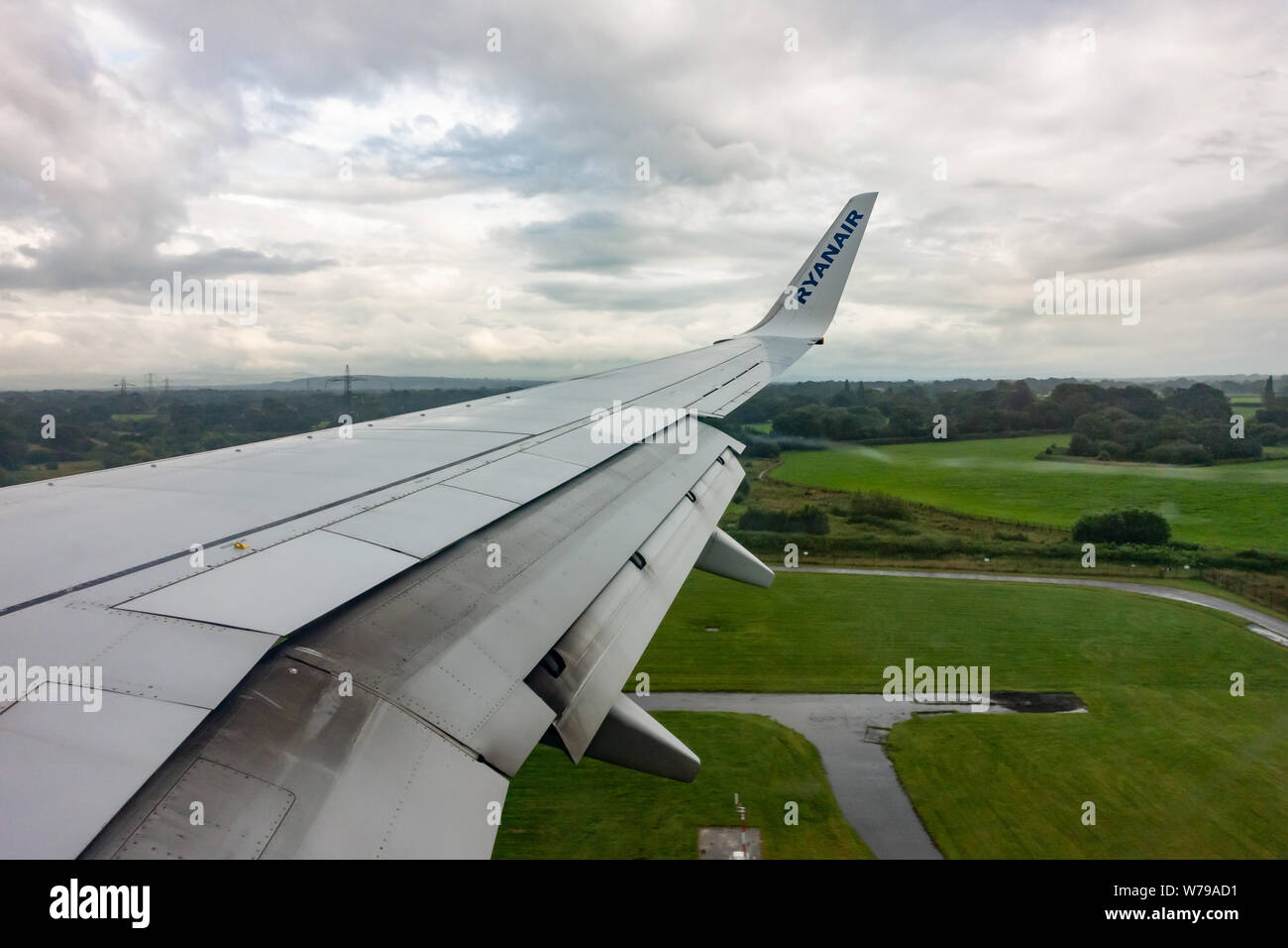 Les volets de l'aile se préparent à ouvrir sur un Boeing 737 de Ryanair - 800 pour un atterrissage sous la pluie sur la piste de l'aéroport de Manchester Banque D'Images