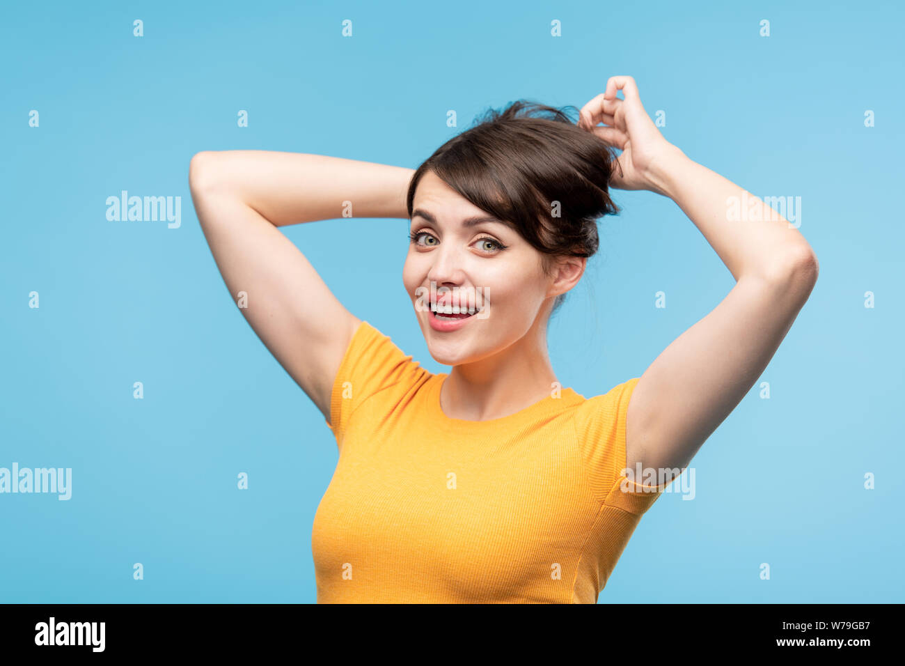 Charmante jeune femme aux cheveux noirs faisant hairstyle dans l'isolement Banque D'Images