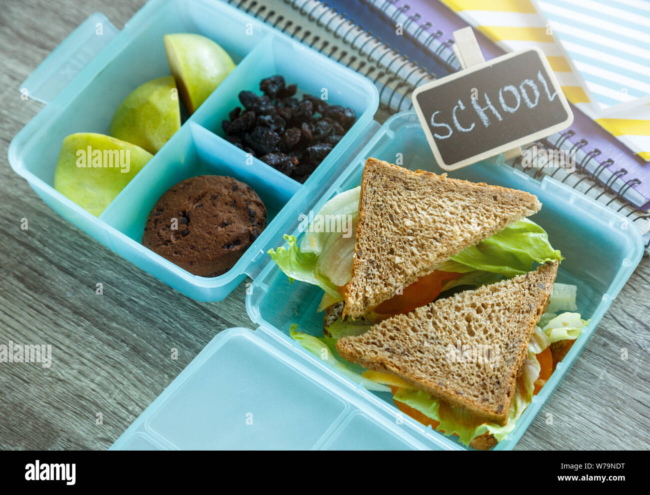 School lunch box bleu composé de sandwich, pomme verte, cookies, crayons, horloge, ordinateurs portables sur la table. Une saine alimentation à l'école. Retour à l'école Banque D'Images