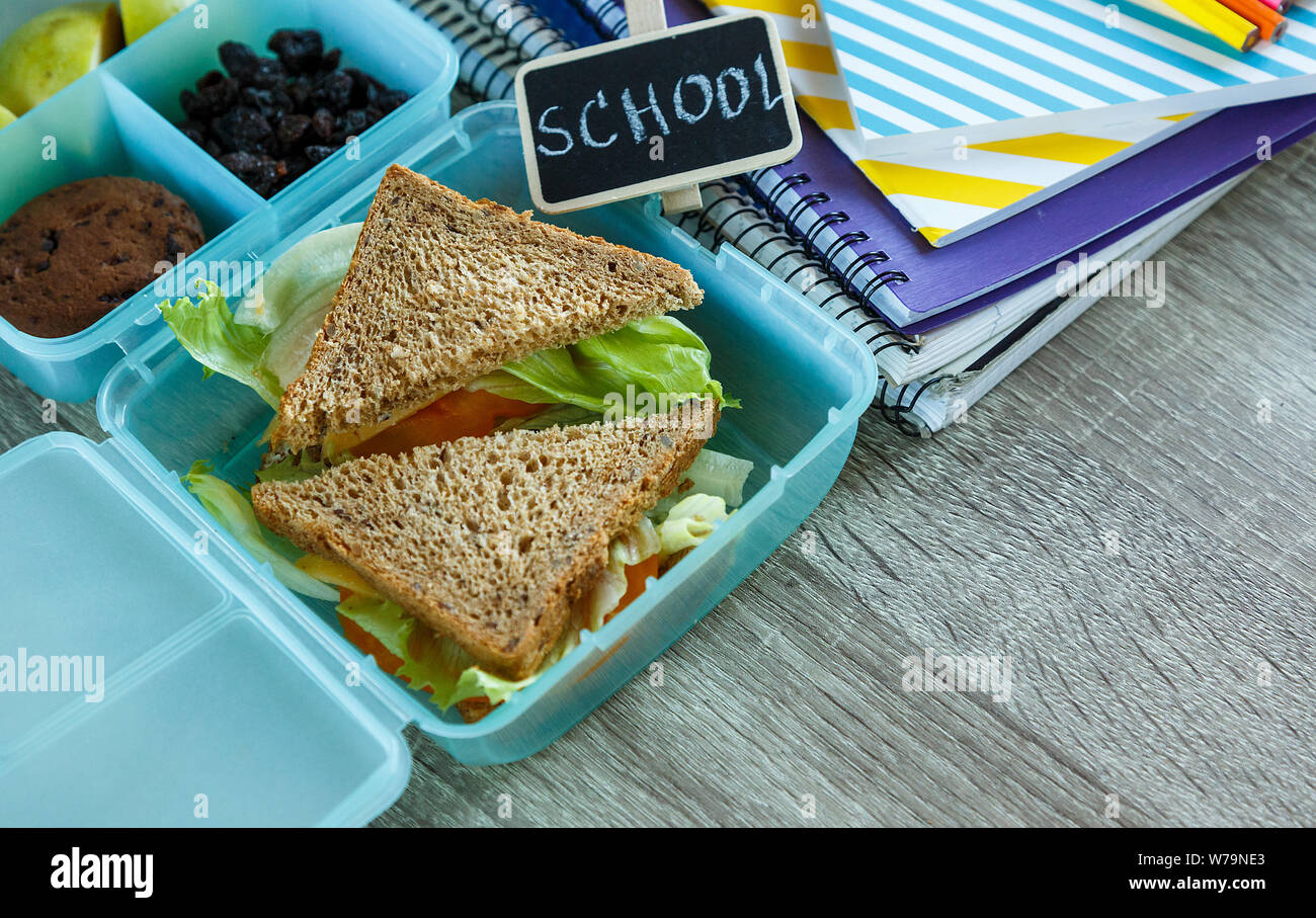 School lunch box bleu composé de sandwich, pomme verte, cookies, crayons, horloge, ordinateurs portables sur la table. Une saine alimentation à l'école. Retour à l'école Banque D'Images