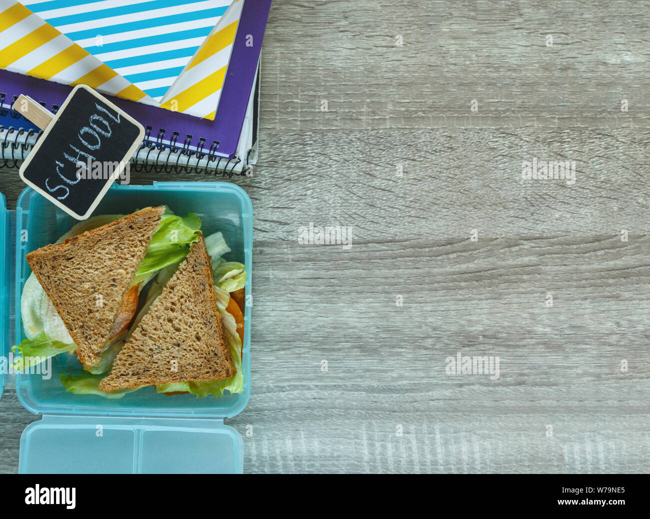 School lunch box bleu composé de sandwich, pomme verte, cookies, crayons, horloge, ordinateurs portables sur la table. Une saine alimentation à l'école. Retour à l'école Banque D'Images