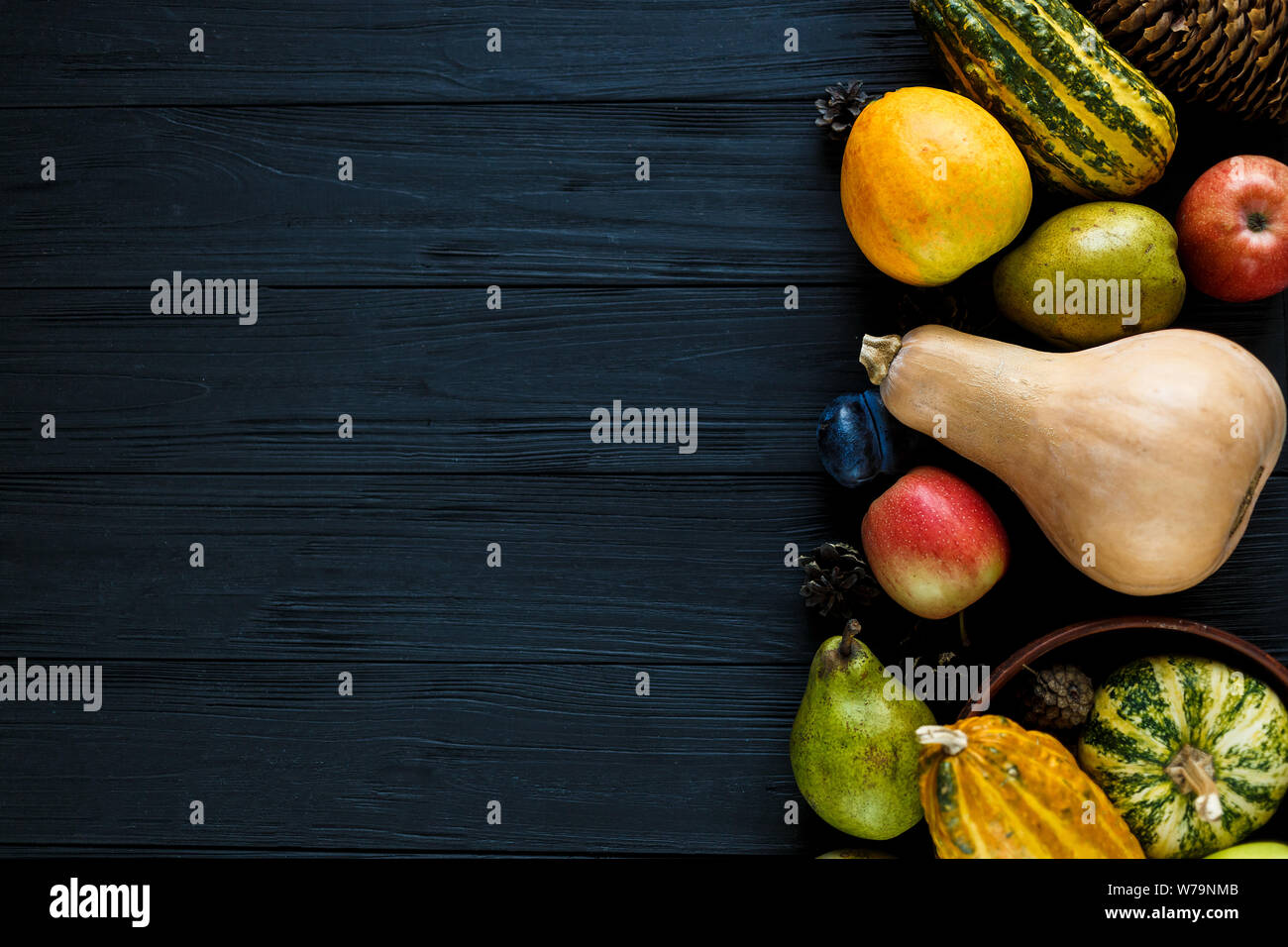 Les citrouilles, les poires, les prunes, les pommes sur la table en bois noir, vue de dessus, l'espace libre pour le texte. Thanksgiving Day journée composition de fruits et légumes sur dark woo Banque D'Images