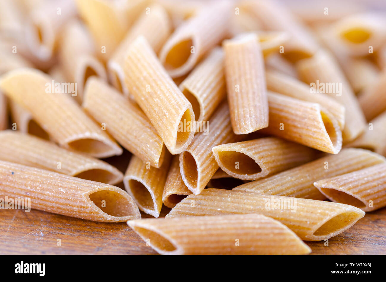 Close up de penne des pâtes alimentaires de blé entier sur table en bois. Banque D'Images