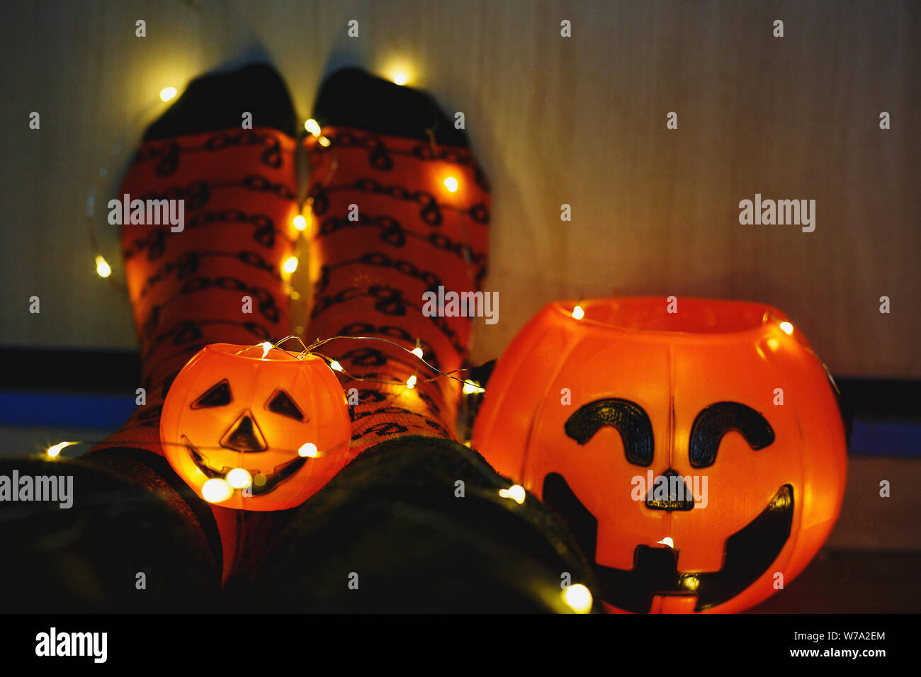 Les enfants dans les jambes chaudes élégante à rayures colorées lumineuses funny chaussettes dans Garland phares sur marbre avec des citrouilles en prix. décoration pour Halloween, cosy chaleureux. Banque D'Images