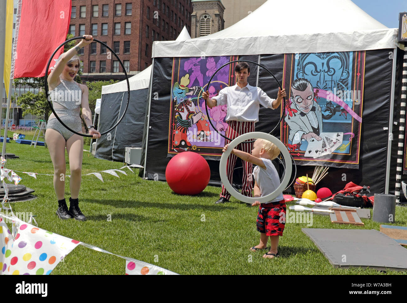 Les artistes néo-vaudevlile jouer avec un garçon aux cheveux blonds et à l'extérieur de leur performance tente sur la place publique dans le centre-ville de Cleveland, Ohio, USA. Banque D'Images