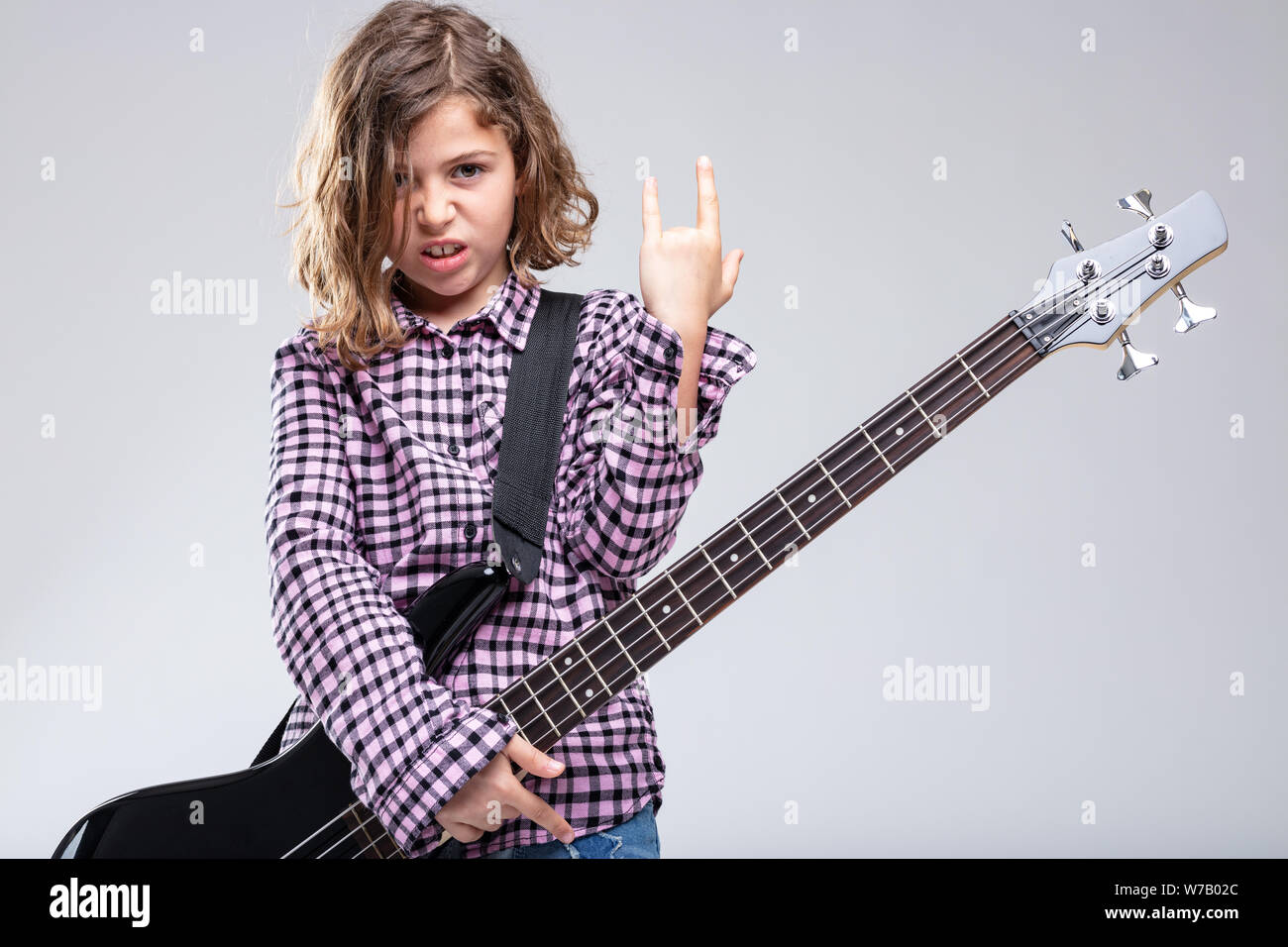 Young Girl playing electric guitar donnant un signe ou un geste des cornes du diable avec sa main pour heavy metal et rock genre avec une vive déterminé ex Banque D'Images