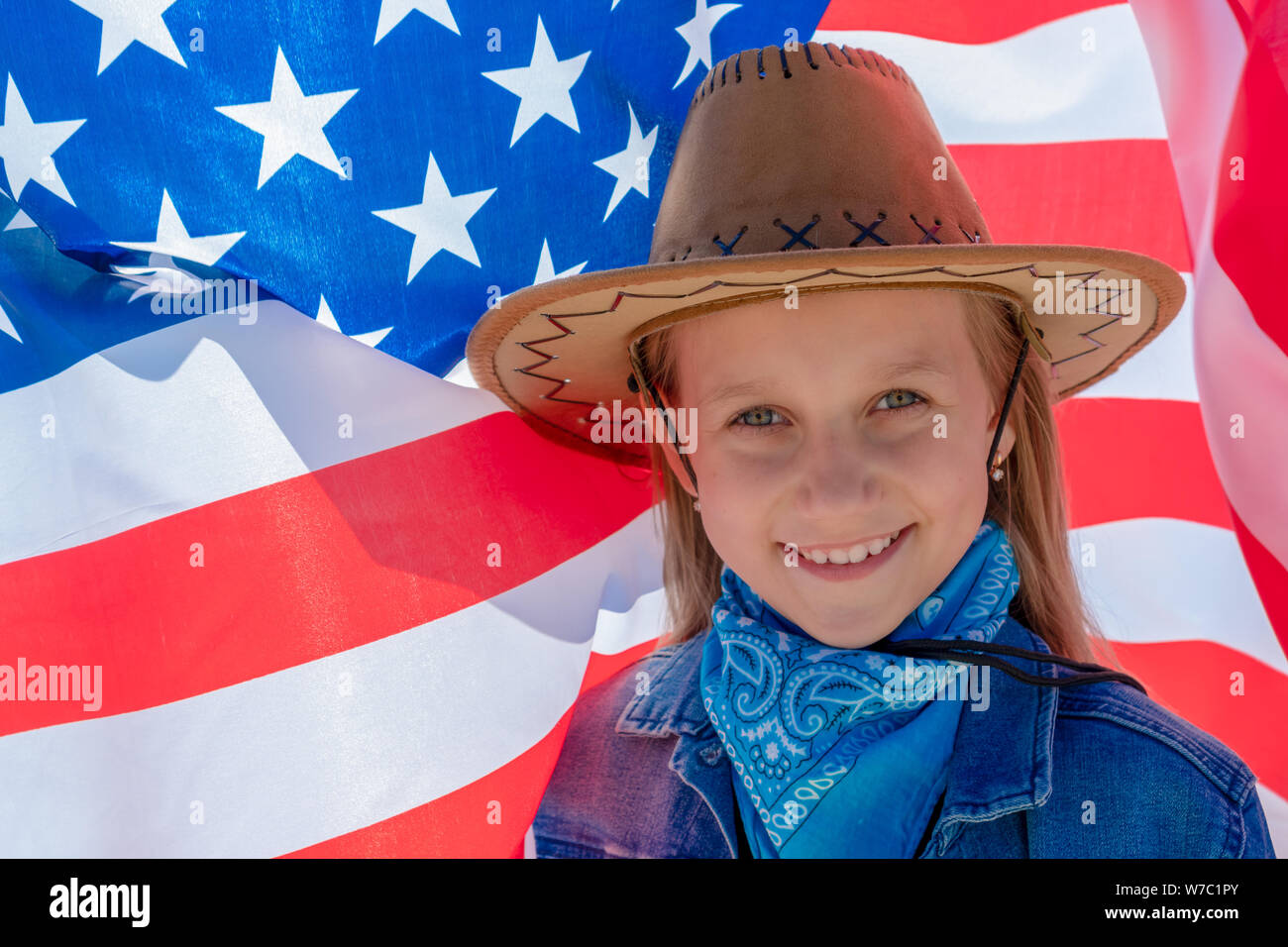 Jour de l'indépendance. Maison de vacances patriotique. Beautiful happy girl aux yeux verts sur le fond du drapeau américain sur une journée ensoleillée. Une fille dans un co Banque D'Images