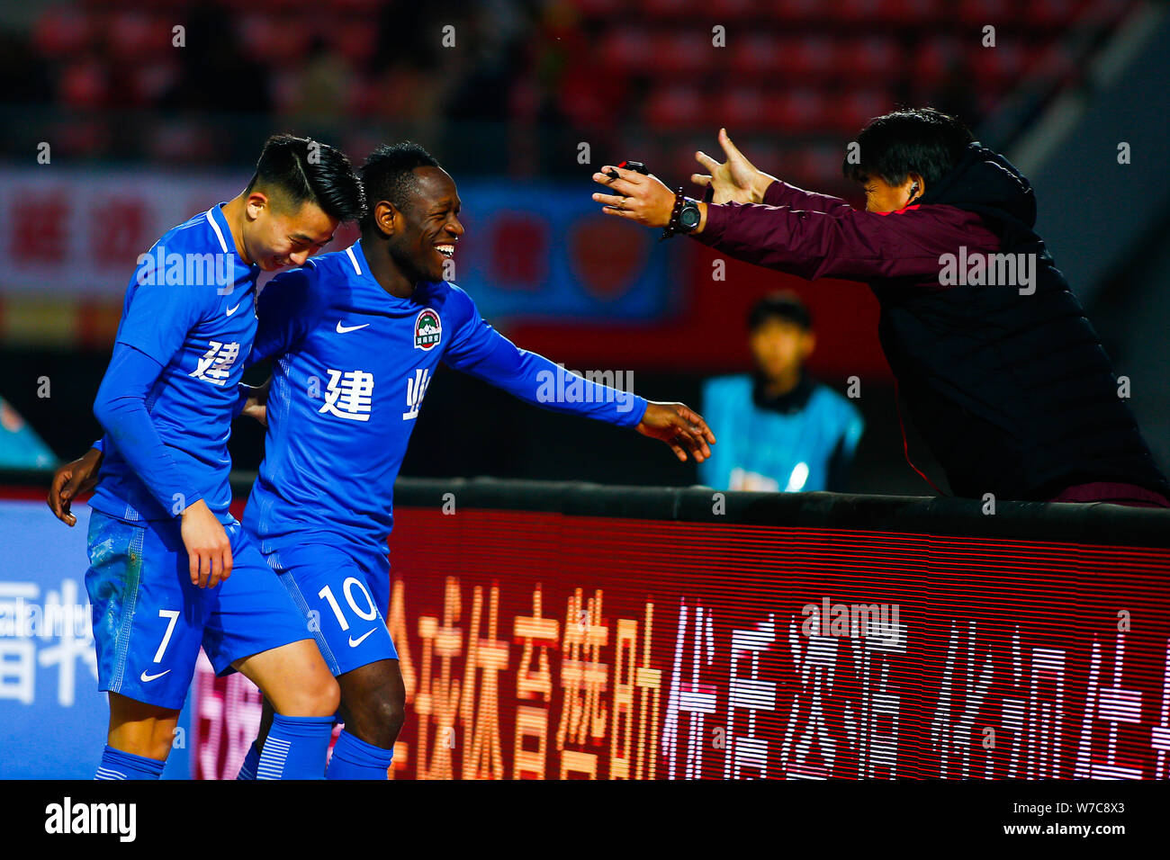 Joueur de football camerounais Christian Bassogog de Henan Jianye, centre, célèbre avec son coéquipier Hu Jinghang et leur entraîneur, Guo Guangqi après sco Banque D'Images