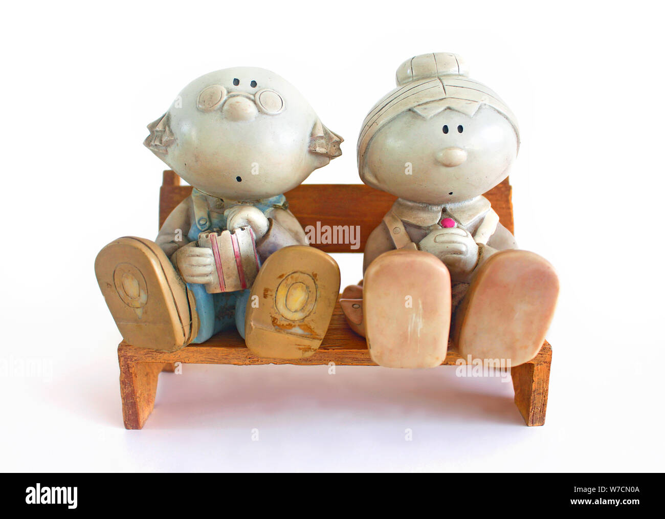 Figurine de couple âgé assise sur un banc en bois, sur fond blanc. Banque D'Images