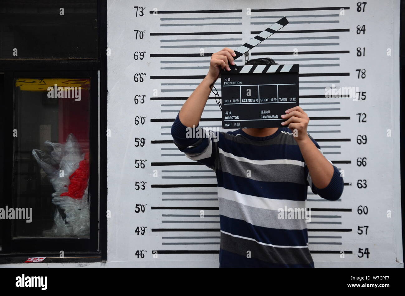 Un client chinois pose pour mugshots en face d'un tableau à la hauteur d'un restaurant sur le thème de la prison dans la ville de Weifang, province de Shandong, Chine orientale, 22 oct. Banque D'Images