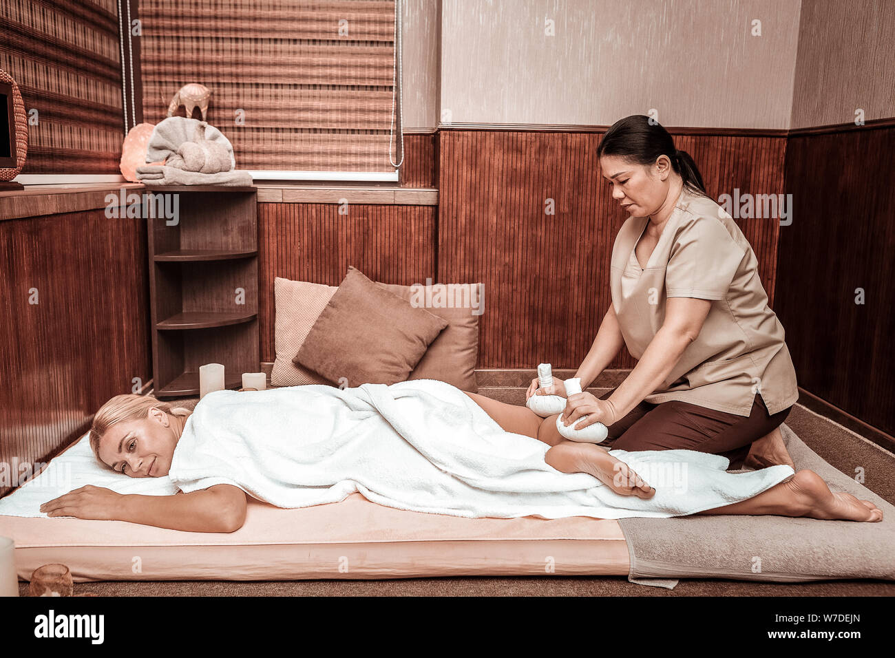 Femme couchée sur un tapis pendant son sac massage. Banque D'Images