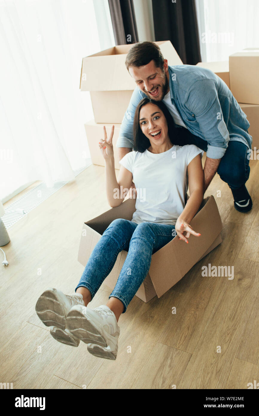 Mixed Race couple s'amusant avec des boîtes de carton tout en se déplaçant à nouveau la maison. Banque D'Images