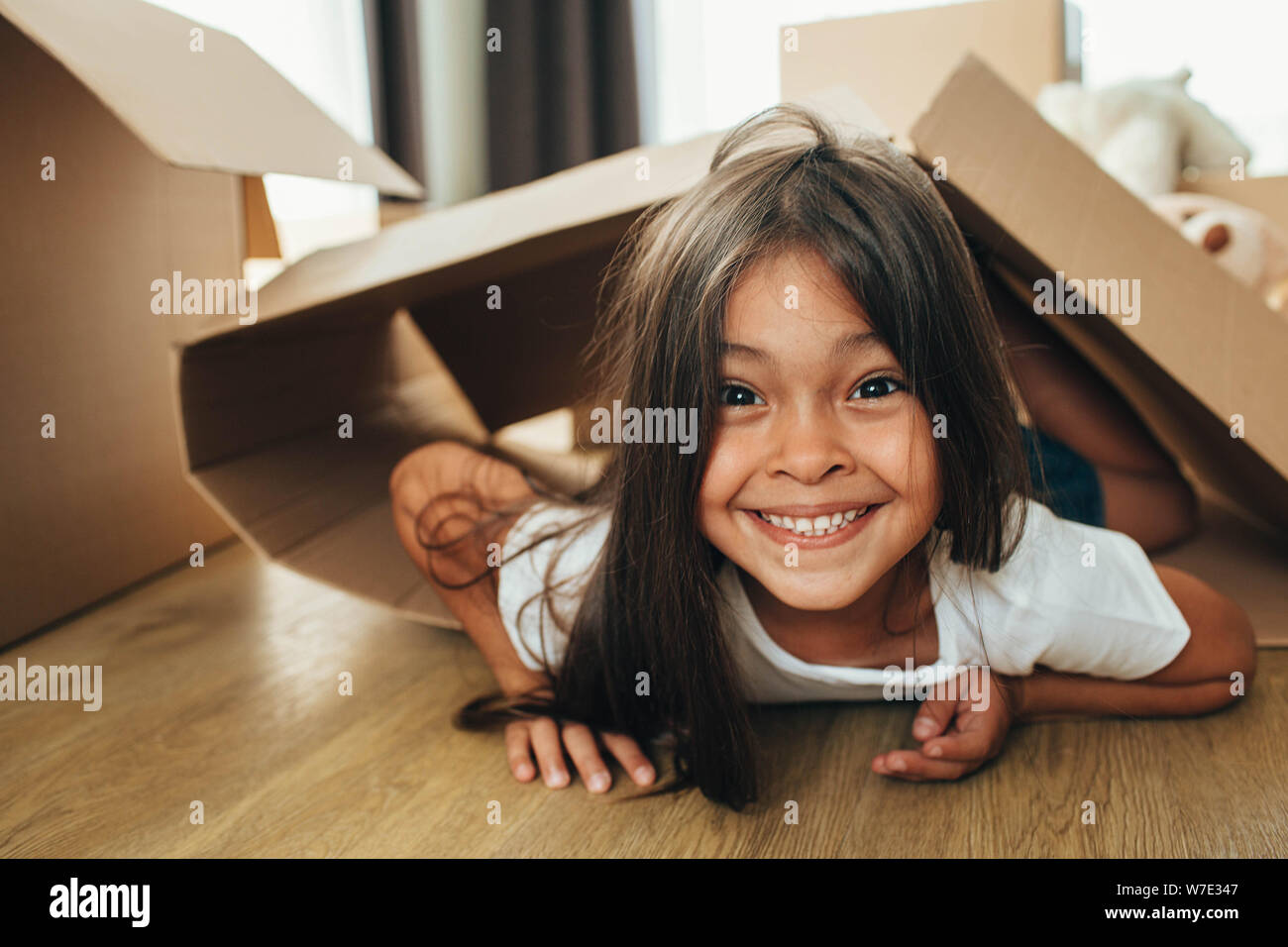 Happy mixed race petite fille jouant avec des boîtes en carton, de s'amuser tout en se déplaçant accueil Banque D'Images