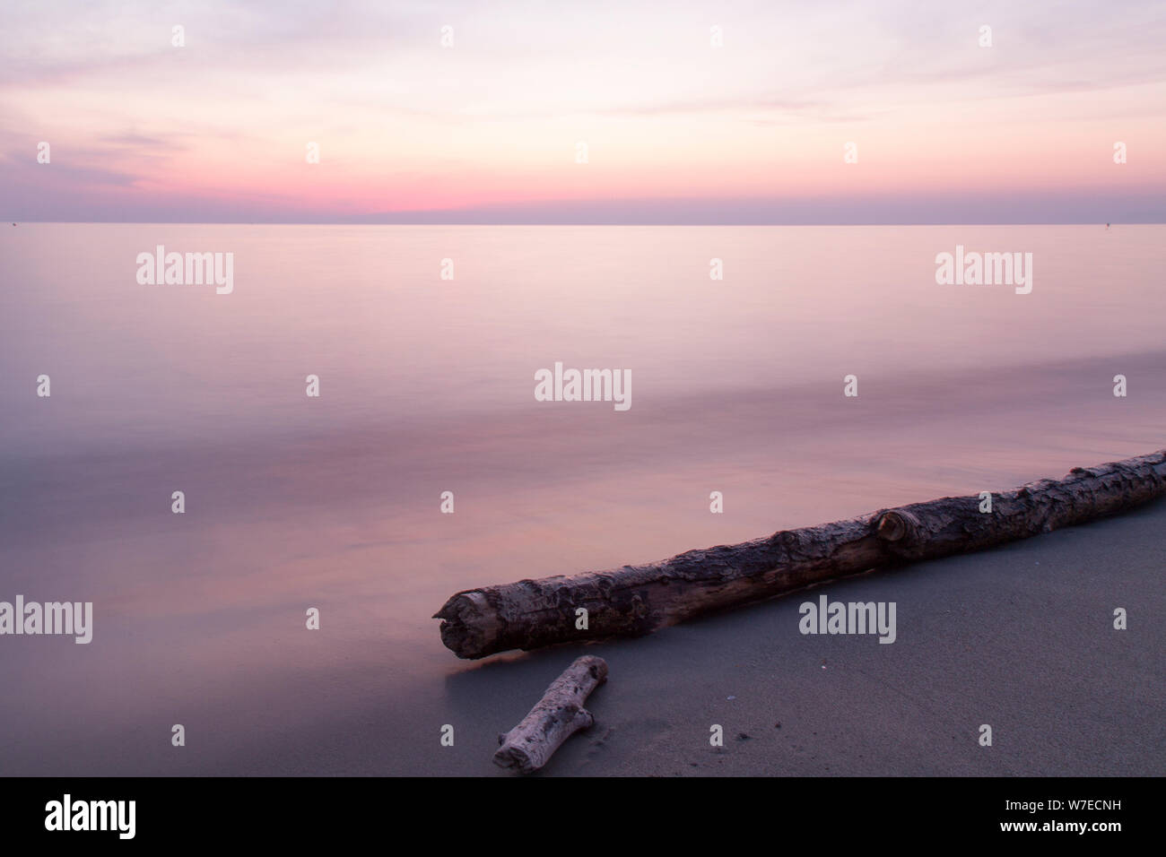 Paysage : l'Italie, sur la plage au coucher du soleil avec tronc d'arbre Banque D'Images