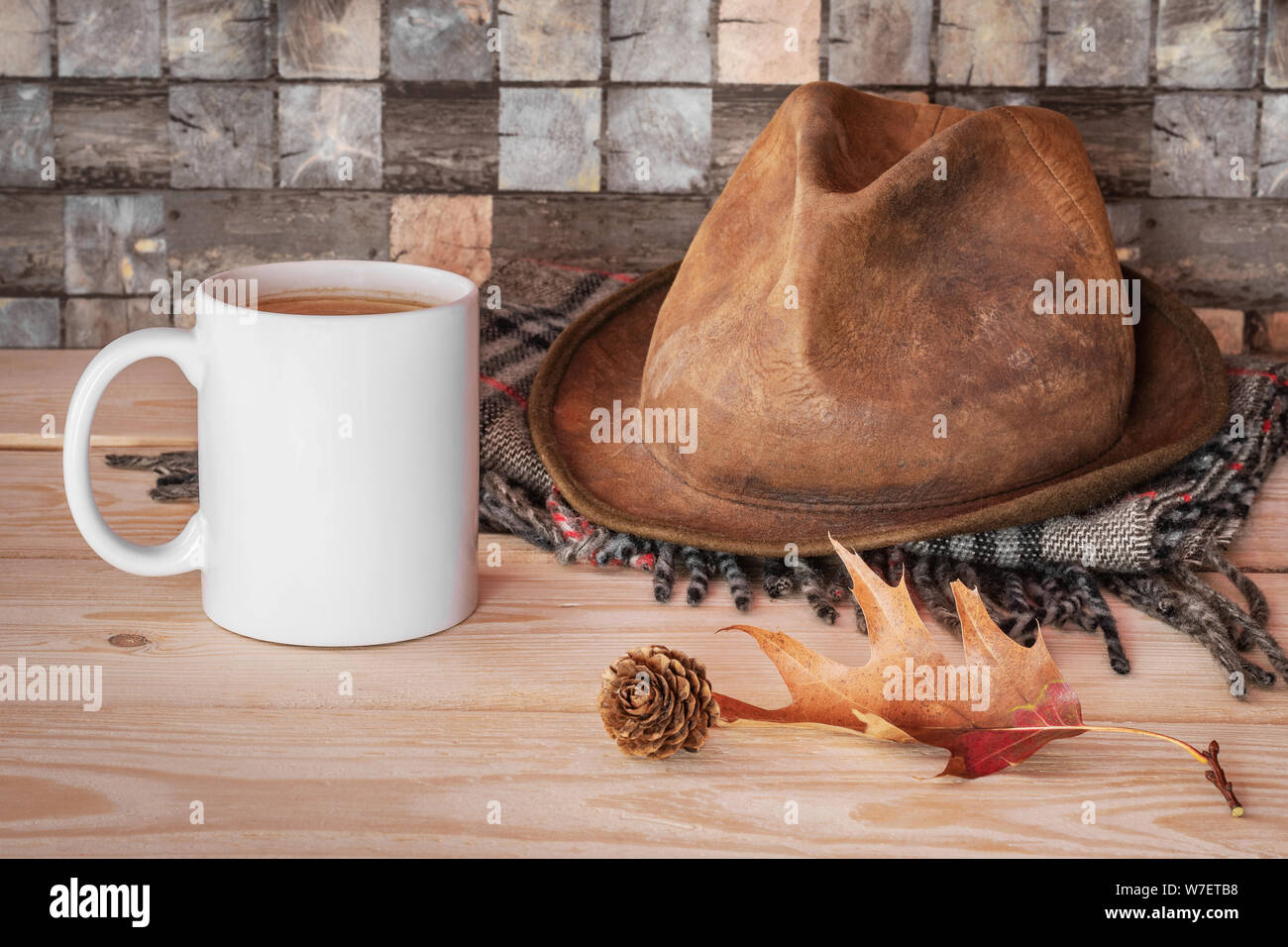 Style scandinave lagom. Tasse de café blanc à carreaux gris avec écharpe,  le vieux cuir chapeau, tombé et feuilles de pin sur table en bois avec bac  à carreaux Photo Stock -
