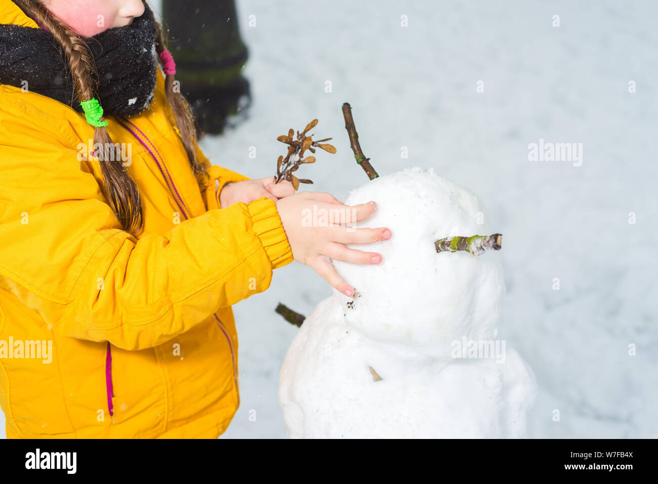 Petite fille faisant un bonhomme de neige. mains étaient froides sans gants Banque D'Images