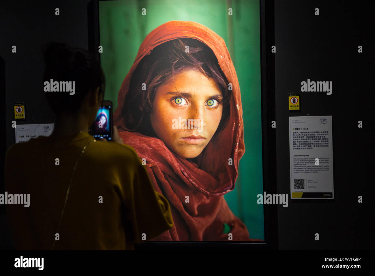Un visiteur prend des photos d'un magazine National Geographic 1985 'Couverture' fille afghane Sharbat Gula affichées à l'exposition National Geographic à Xi'un Banque D'Images